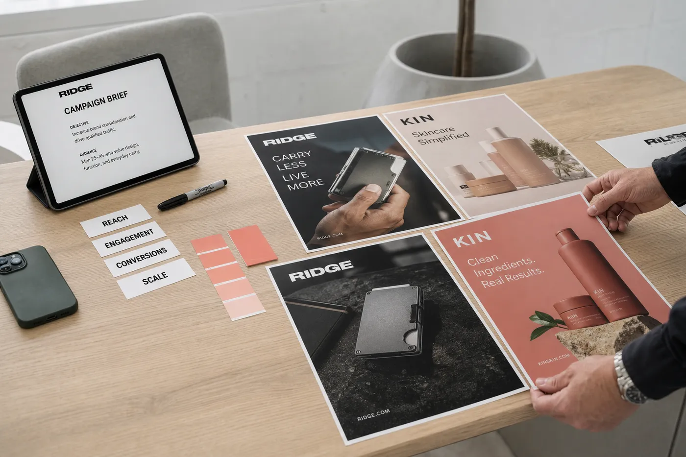 Campaign desk with printed creatives and reach, engagement, conversions and scale labels